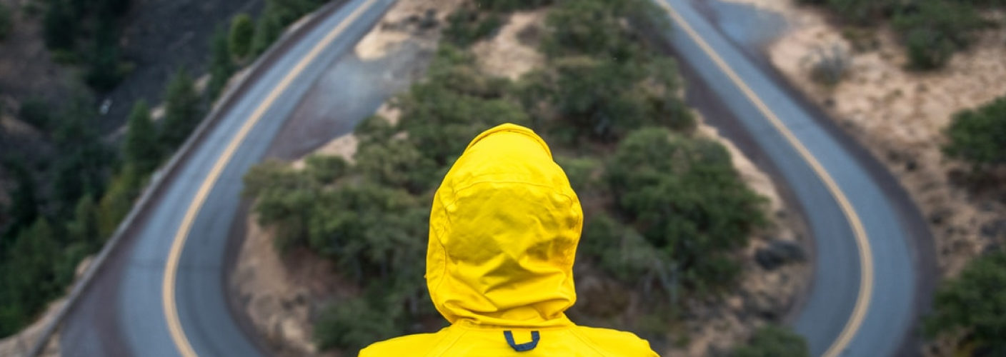 Person sitting sitting beside a road winding through a mountain scene