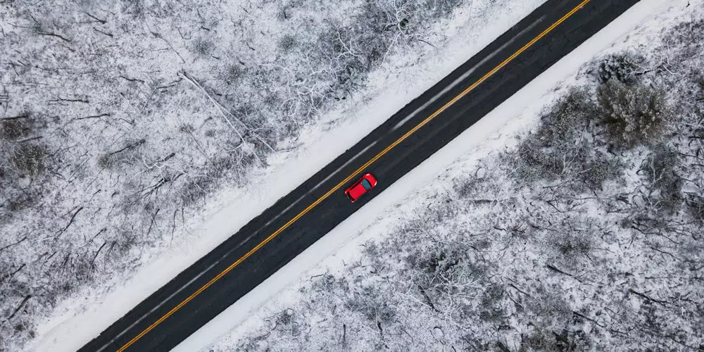 Birds eye view of a red car driving in winter