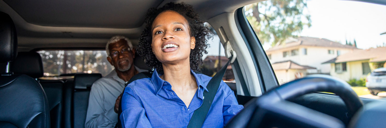 Young driver with parent in backseat