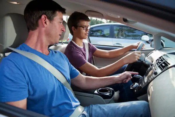 Child learning driving basics with parent