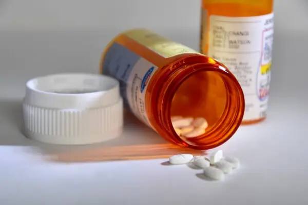Open medication bottle with pills on a table