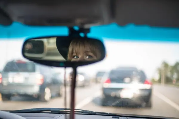 Woman looking in rearview mirror while driving
