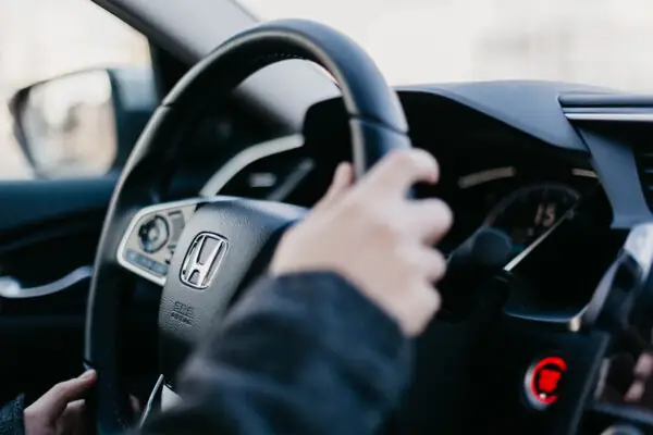 person with hands on a car steering wheel