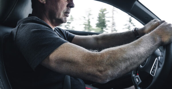 man driving intensely with hands on the wheel